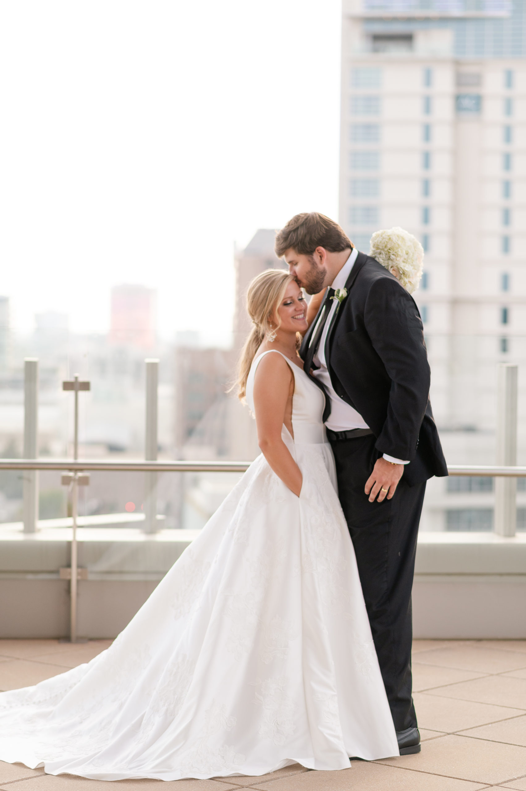 groom kissing brides temple on rooftop