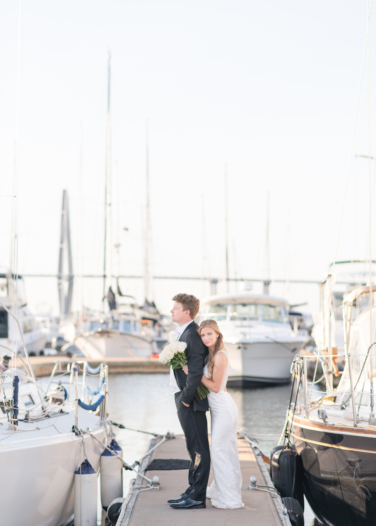Bride hugging her groom standing on a boat dock